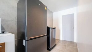 A modern kitchen with a large black refrigerator and a smaller one, a white countertop, and a door in the background. - Villa 35 Wongamat 4 BR, 300m from BEACH (Pattaya City)