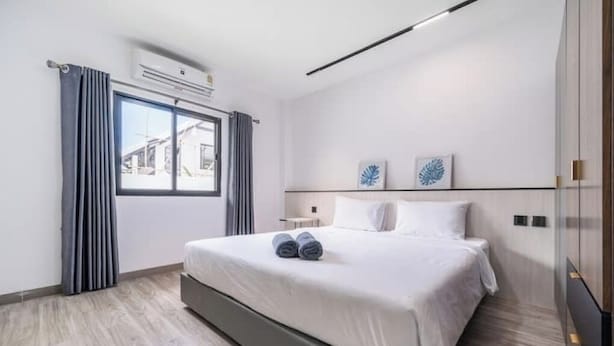 Ein modernes Hotelzimmer mit einem großen Bett, einem Fenster mit Vorhängen und zwei an der Wand befestigten Kunstwerken.