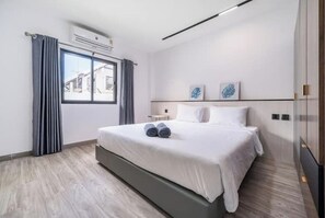 Une chambre d’hôtel moderne avec un grand lit, une fenêtre avec des rideaux et deux œuvres d’art accrochées au mur.