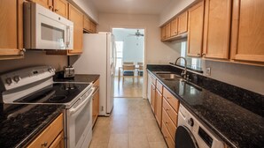A kitchen with wooden cabinets, a microwave, stove, and a washing machine. - Guard Gated Golf Course 1mi to Vegas Strip Best Kept Secret Quiet Secure 9 (Las Vegas)