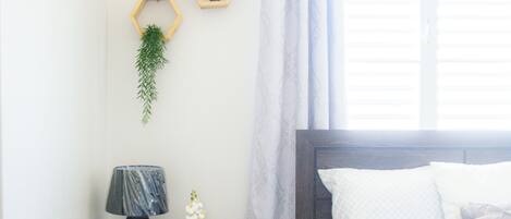 Un dormitorio con una cama, una mesita de noche con lámpara y dos decoraciones hexagonales en la pared.