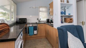 Une cuisine de taille réduite, équipée d’un four à micro-ondes, d’un évier et de meubles de rangement en bois.
