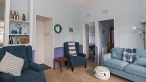 Un salon avec deux canapés, une petite table et une étagère décorative fixée au mur.