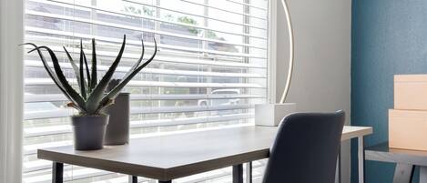 A modern room with a window, a desk, a chair, and a potted plant.