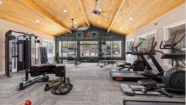 Ein Fitnessraum mit Deckenventilatoren, Laufbändern und Gewährleistungsequipment.