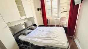 Una habitación pequeña con cama, escritorio y silla.