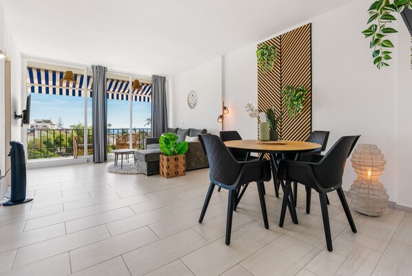 A modern dining area with a round table, black chairs, and a potted plant.