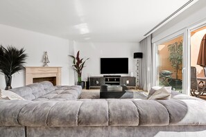 Un salon moderne avec un grand canapé d’angle, un téléviseur à écran plat et une cheminée.