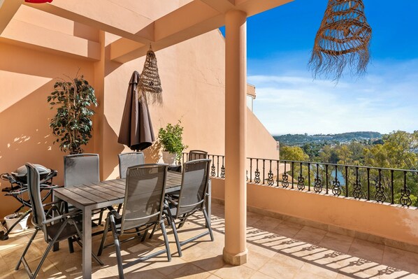 Un balcon avec une table et des chaises, un luminaire suspendu et une vue sur le paysage urbain.