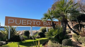 Un panneau indiquant l’entrée de Puerto Ballas, avec une vue sur la mer et un jardin aménagé.