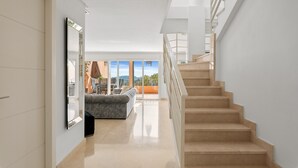 Un interior moderno con una escalera, un sofá y un ventanal que ofrece vistas.