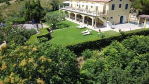 A large, yellow building with a covered outdoor area and a well-maintained lawn. - AGRITURISMO MONTEMAGGIO (Lapedona)