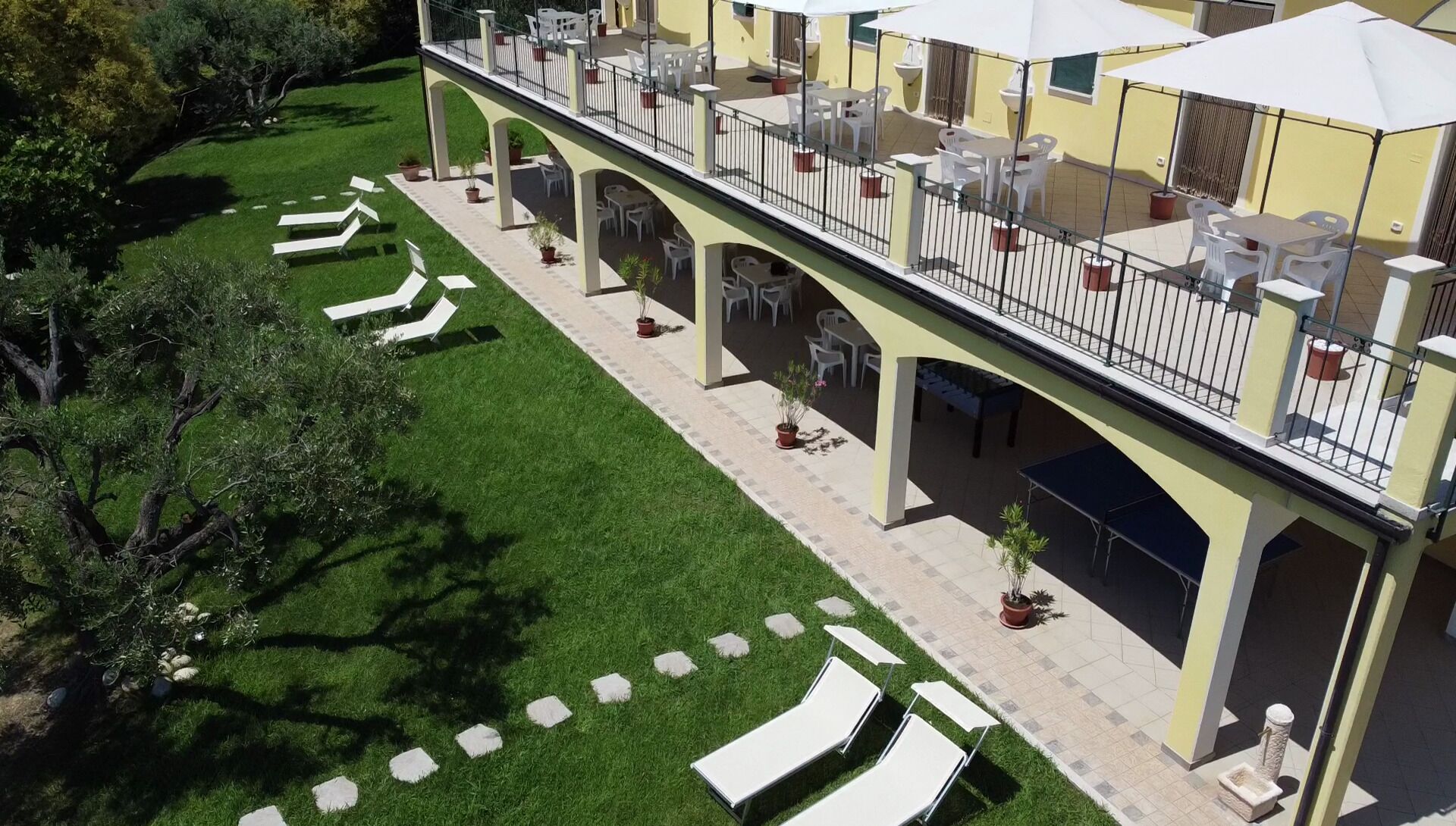 Un hôtel doté d’un espace extérieur couvert avec des sièges, de plusieurs chaises longues et d’une pelouse bien entretenue.