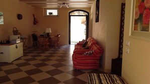 A cozy living room with a checkered floor, a red sofa, and a dining area with a table and chairs. - AGRITURISMO MONTEMAGGIO (Lapedona)