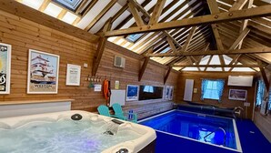 A hot tub and a pool in a wooden cabin with a sloped ceiling and framed pictures on the walls. - 1 Bed Cabin-sleeps 2, Hot Tub, Garden, Pets, Views (Callington)