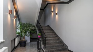 Eine moderne Treppe mit schwarzer Geländer, einem Topfpflanzen und einem kleinen Tisch mit einem rosafarbenen Topf.