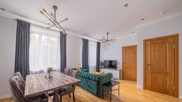 Ein modernes Wohnzimmer mit einem Holzesstisch, einem grünen Sofa und einem Fernseher.