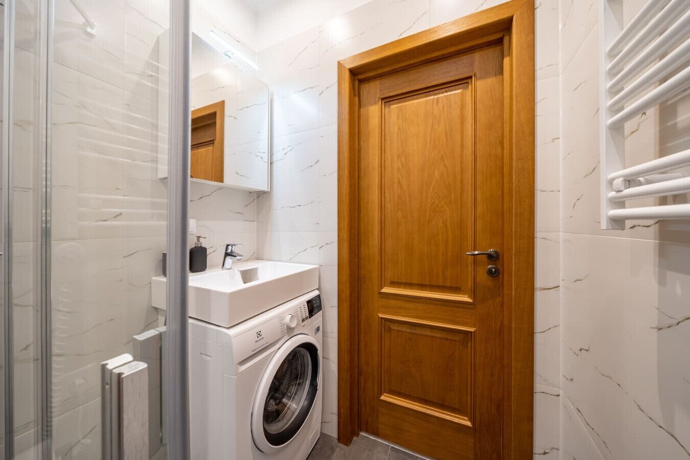 Une petite salle de bain équipée d’un lave-linge, d’un évier et d’une porte en bois.