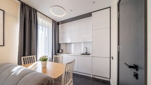 A modern kitchen with white cabinets, a black countertop, and a stainless steel sink. - Beach and forest front apartment in Dzintari (Jūrmala)