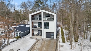 A modern multi-story building with a flat roof, large windows, and a balcony. - THE FRISKY BEAVER - Spacious, modern cottage in Grand Bend (Lambton Shores)