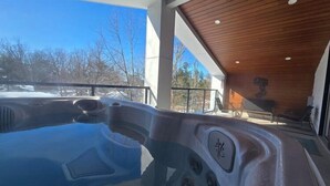 A hot tub in a covered outdoor area with a view of trees and a clear sky. - THE FRISKY BEAVER - Spacious, modern cottage in Grand Bend (Lambton Shores)