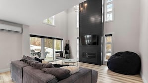 A modern living room with a sectional sofa, a black bean bag, a TV, and a fireplace. - THE FRISKY BEAVER - Spacious, modern cottage in Grand Bend (Lambton Shores)
