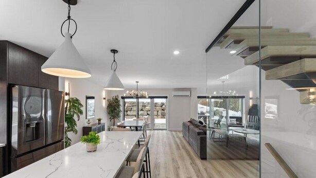 A modern kitchen with a marble countertop, pendant lighting, and a built-in oven. - THE FRISKY BEAVER - Spacious, modern cottage in Grand Bend (Lambton Shores)