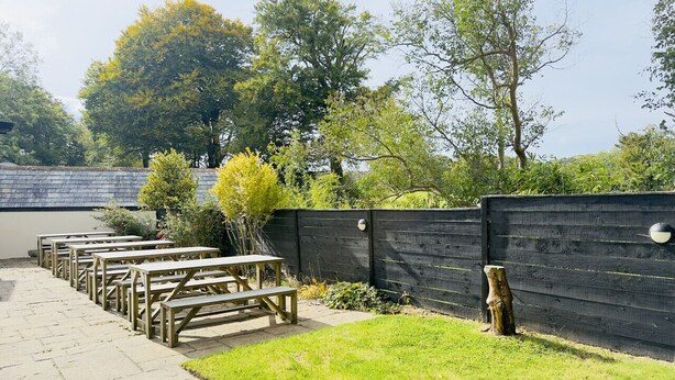 A picnic area with wooden benches and a black fence.