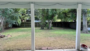Un espacio de patio techado con vista al jardín trasero.