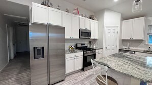 Una cocina moderna con electrodomésticos de acero inoxidable, armarios blancos y encimera de mármol.
