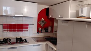 Een kleine keuken met een gasfornuis, een magnetron en een spoelbak.