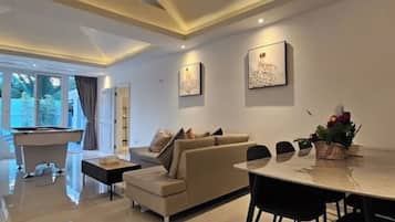 Una sala moderna con sofá, mesa de comedor y mesa de billar.