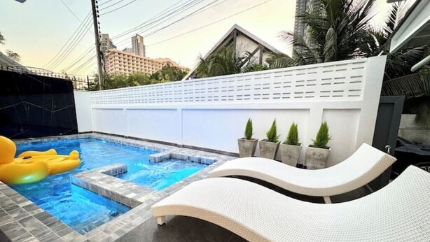 A swimming pool with a white lounge chair and yellow inflatable rings.