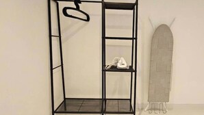 A black metal shelf unit with a hanging hook and a white telephone on one of the shelves.