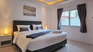 A modern hotel room with a large bed, a bedside table, a nightstand, a window with curtains, and a painting on the wall.