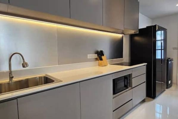 A modern kitchen with a stainless steel sink, grey cabinets, and a black refrigerator. - Villa 129 Wongamat, 4 Beds. (Pattaya City)