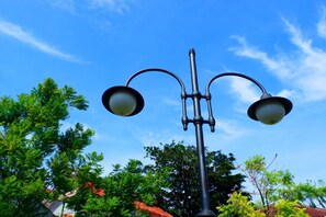 A street lamp with two lights, surrounded by trees and buildings. - Bianco Costel (Central Bogor)