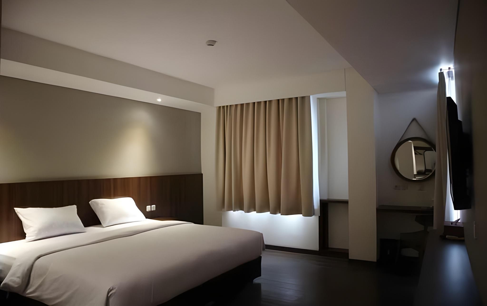 Una habitación de hotel con una cama grande, un espejo y una ventana con cortinas.
