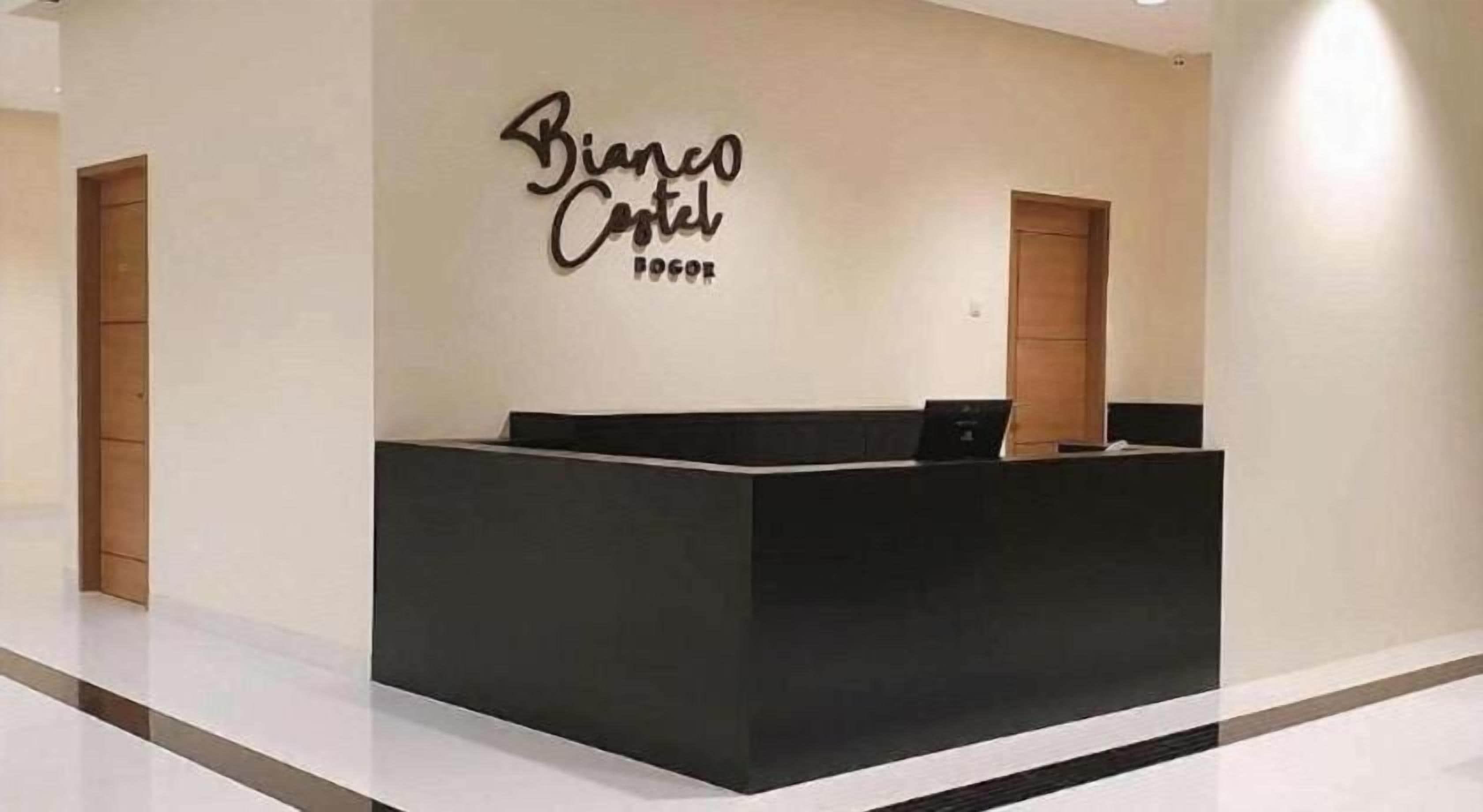 Een receptiebalie met een bord waarop 'Bianco Centro' staat in een moderne hotelentree.