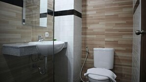 A bathroom with a sink, mirror, toilet, and shower. - Bianco Costel (Central Bogor)