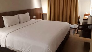 A hotel room with a large bed, a desk, and a chair. - Bianco Costel (Central Bogor)
