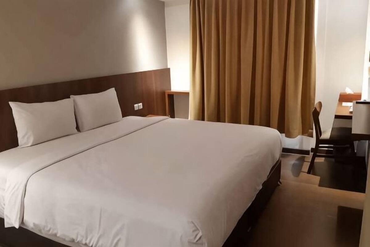 Una habitación de hotel con una cama grande, un escritorio y una silla.