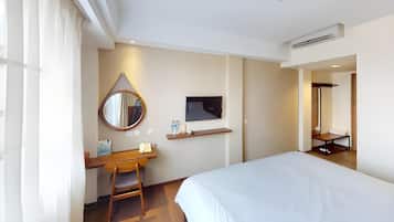 Een hotelkamer met een bed, een bureau, een stoel, een spiegel, een televisie en een plank.