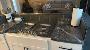 A kitchen with a gas stove, white cabinets, and a marble countertop. - 4 Bed Cozy Home closely located near downtown (Lansing)