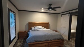 A bedroom with a wooden bed, a ceiling fan, and a sliding door. - Mountain Retreat Near Waterfalls & Hiking Trails – Your Clarkesville Getaway (Clarkesville)