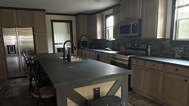 A modern kitchen with a central island, stainless steel appliances, and wooden cabinets. - Mountain Retreat Near Waterfalls & Hiking Trails – Your Clarkesville Getaway (Clarkesville)