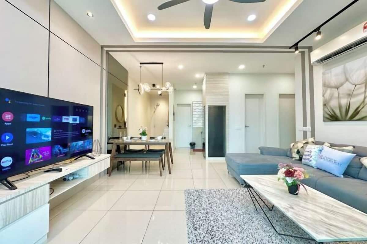 Ein modernes Wohnzimmer mit Flachbildfernseher, Essbereich, einer Couch und Deckenventilator.