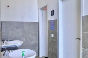 Une salle de bain avec deux lavabos, un miroir et une porte donnant sur une autre pièce.