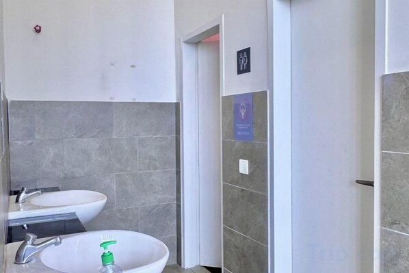 A bathroom with two sinks, a mirror, and a door leading to another room. - Melaka Ong Kim Wee Residences by Stayrene (Melaka)