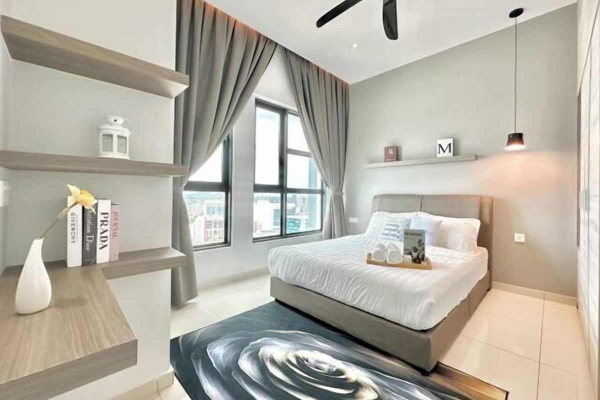 Ein modernes Schlafzimmer mit einem Bett, einem Deckenventilator, einem Fenster mit Vorhängen und einem Regal mit Büchern und einer Vase.